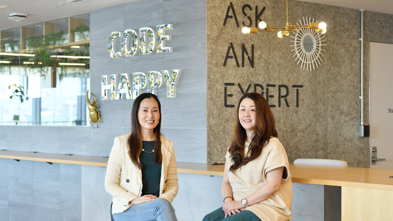 リコチャレを推進した菊池さんと澤さん。後ろの壁には「HAPPY CODE」と「ASK AN EXPERT」の文字