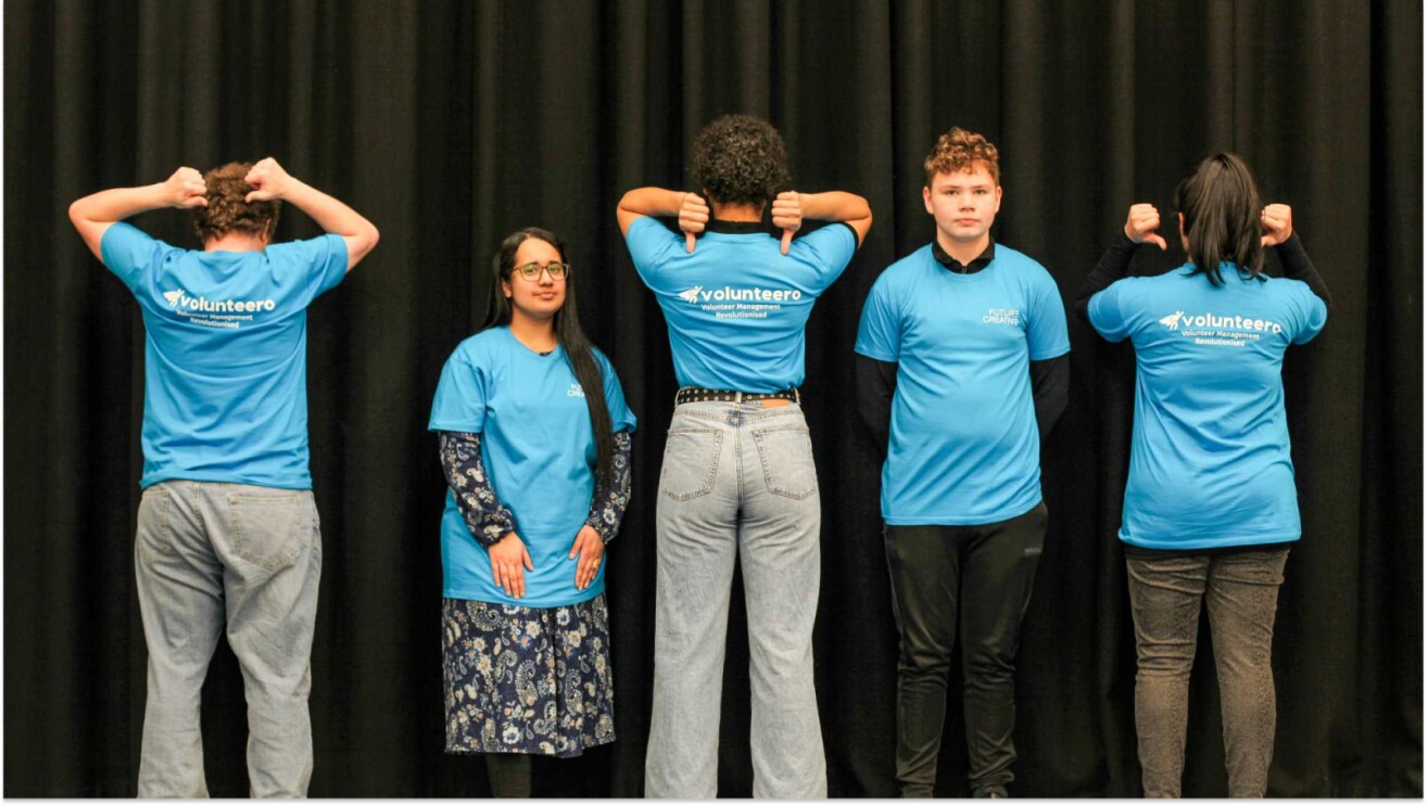 Volunteers in blue shirts standing in a line, some facing away