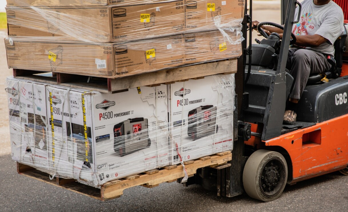 A man working with Amazon's disaster relief team is driving a forklift loaded with generators at the front. These generators will be used to provide power to those affected by recent natural disasters in the U.S.