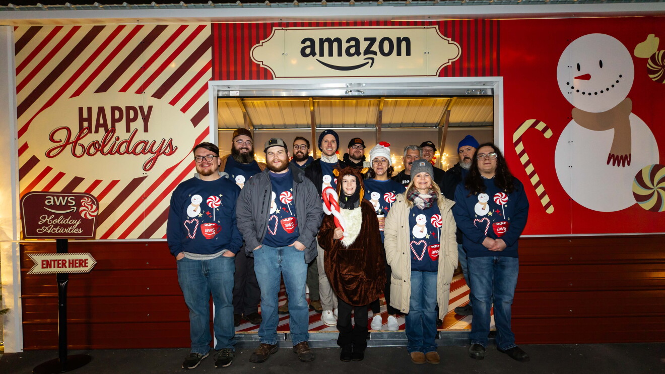 AWS in Communities: Festive Amazon team picture in front of snowman-decorated booth