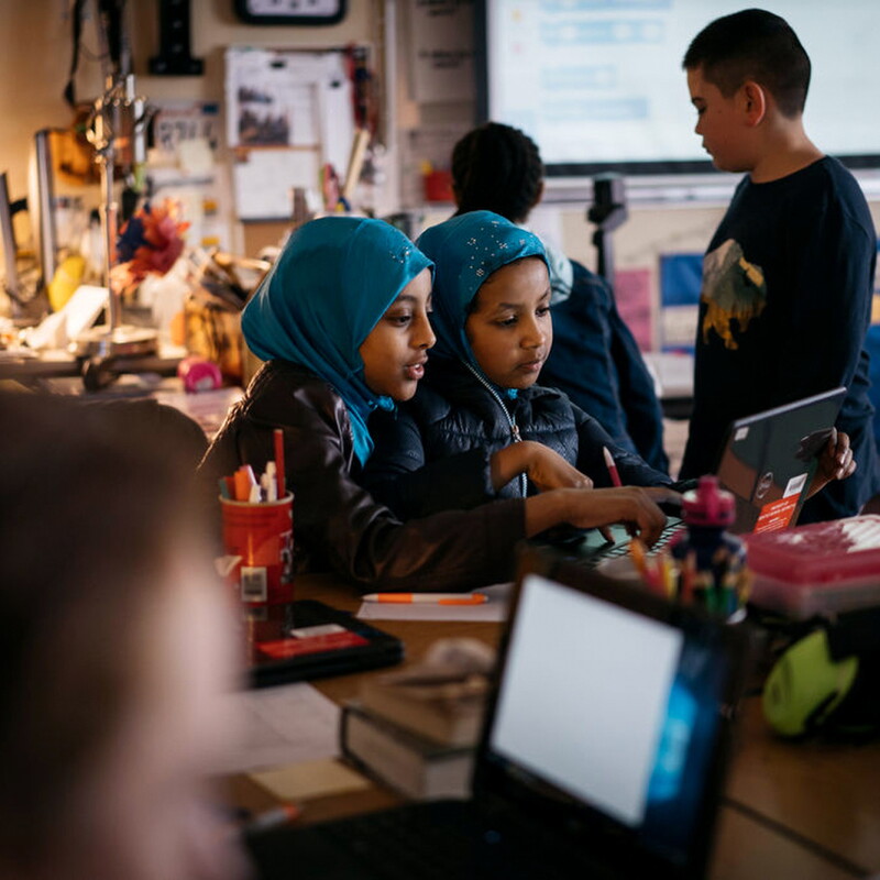 Two students in hijabs study coding at an Amazon-provided laptop