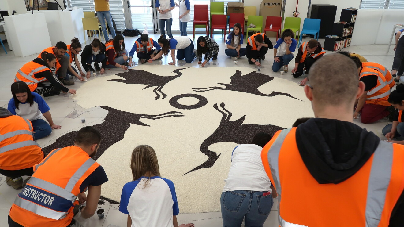 gruppo di dipendenti Amazon del centro di distribuzione di Vercelli seduto in terra attorno ad un Mandala in composizione
