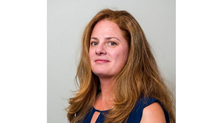 An image of a woman smiling for a headshot photo with a white background behind her.