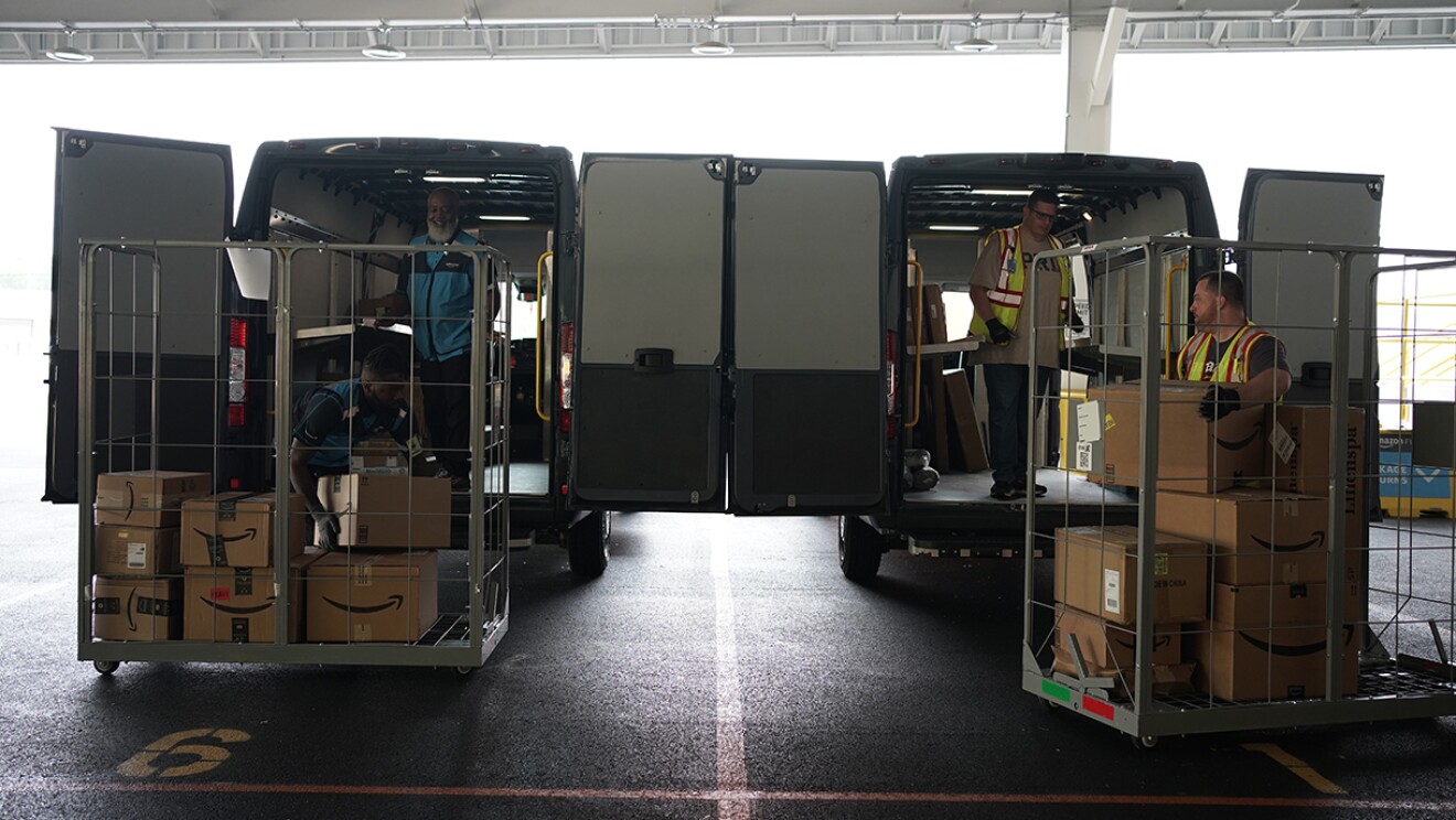 Volunteers and Amazon employees load up Amazon delivery vans with essential furniture and household products.