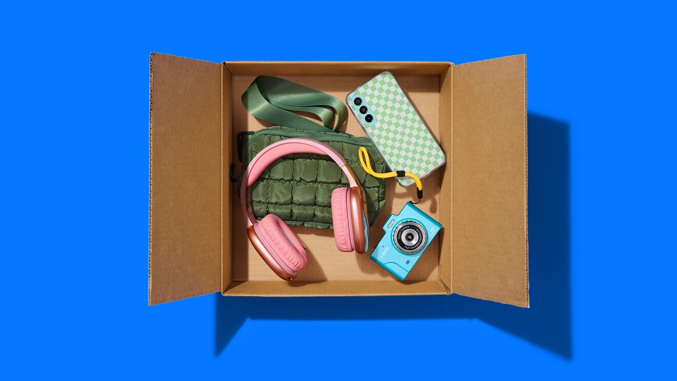 Pink headphones, green bag, camera, and phone in shipping box