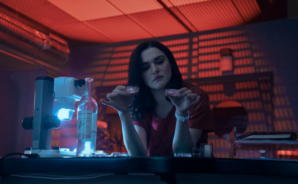 Rachel Weisz holds small petri dishes in a laboratory