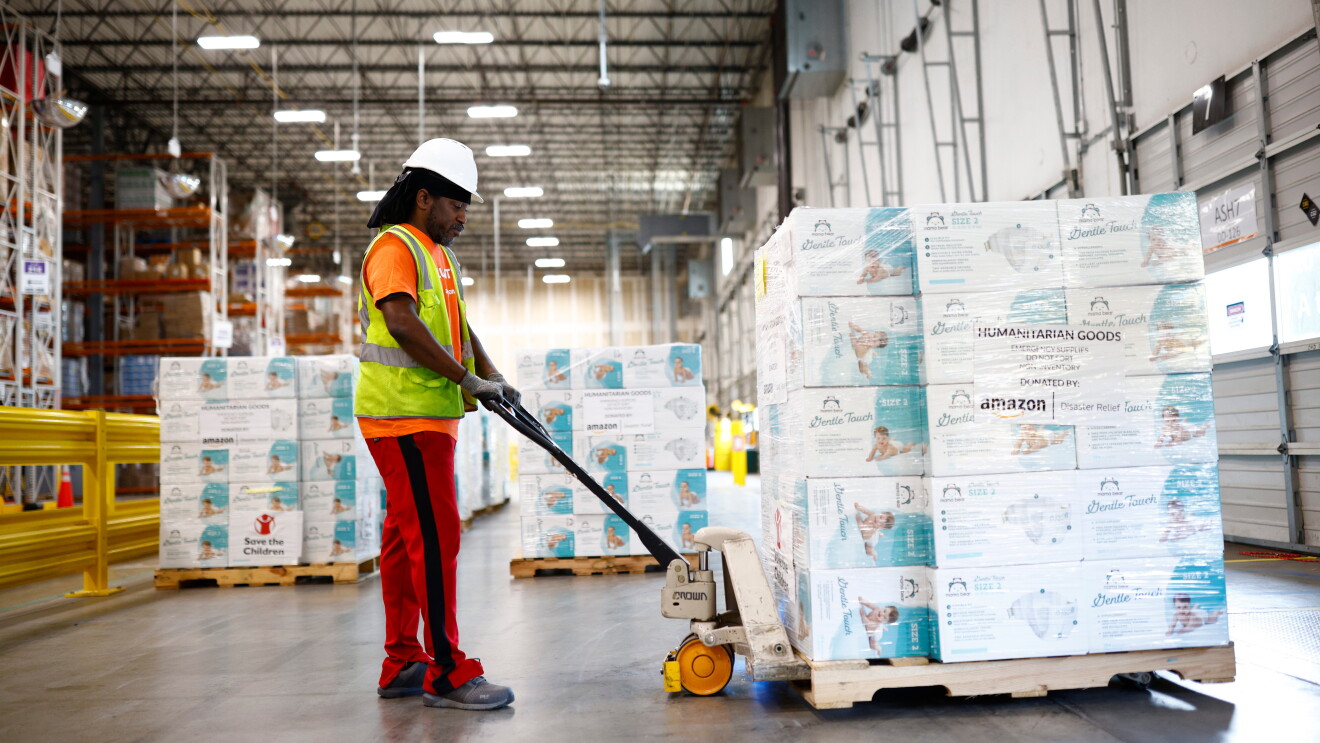 Warehouse worker moving pallet of humanitarian goods donated by Amazon
