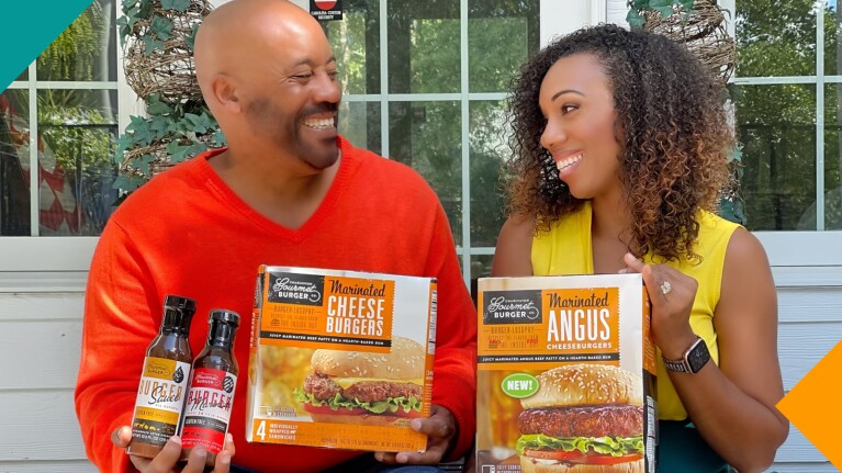 A photo of Charleston Gourmet Burger Co. owners Chevalo and Monique Wilsondebriano holding a box of gourmet burgers and burger sauce.