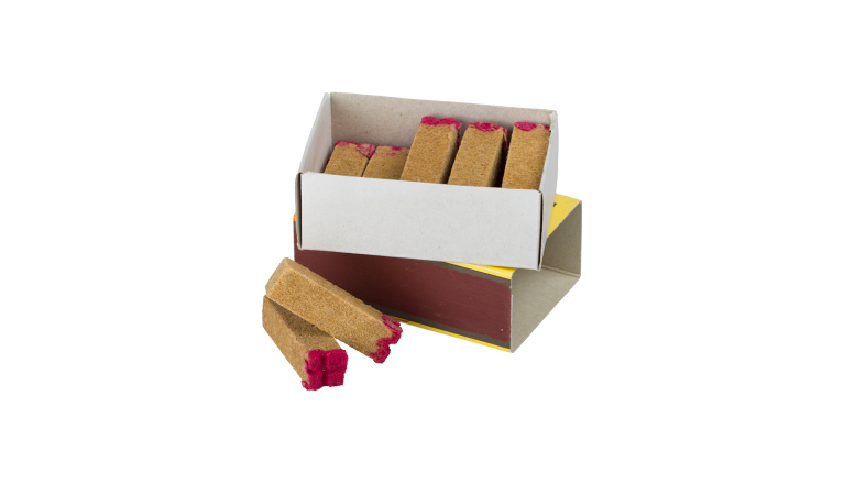 茶色い長方体の上部に赤い粉のようなものが付着している着火剤。それらがマッチ箱の中に入っている