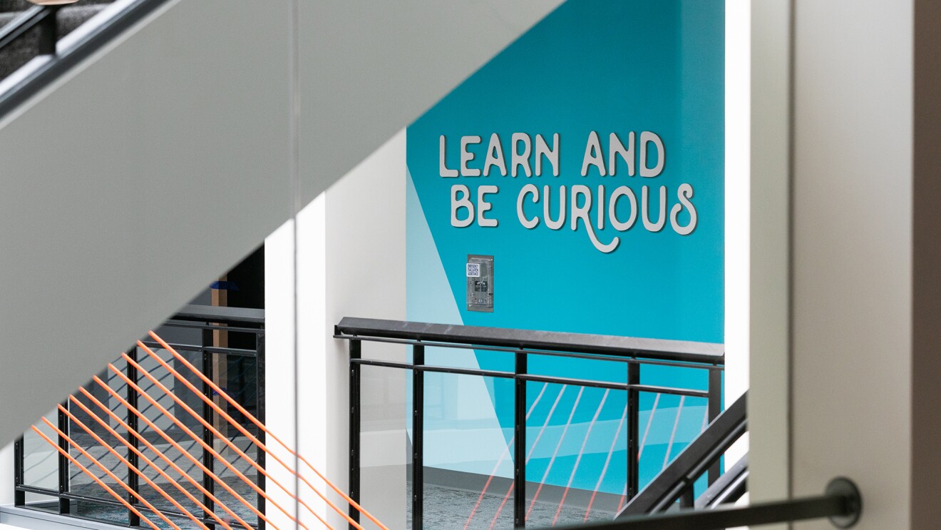 办公空间与蓝色的墙与亚马逊的领导原则“学习和好奇”提高了明亮的蓝色背景的白色字母。