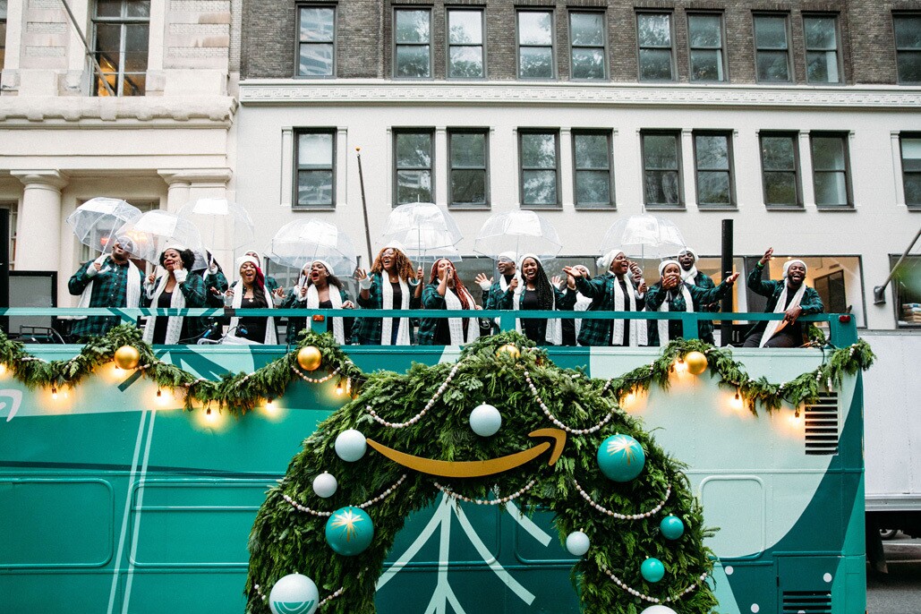 An image of the Harlem Gospel Choir on top of a green double-decker bus singing to crowds in New York.