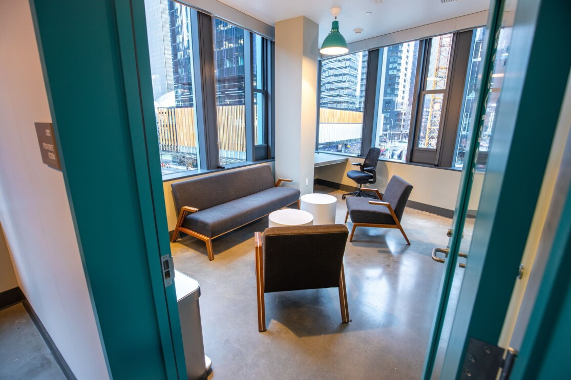 An image of a room with chairs, a small couch, small tables, and large windows along the walls.