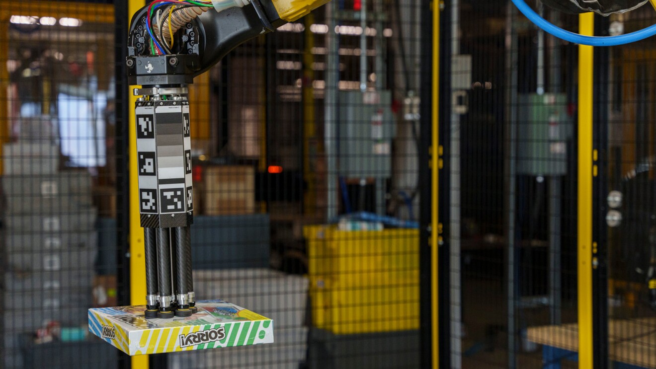 A robotic arm moves products from a bin in an Amazon fulfillment center.