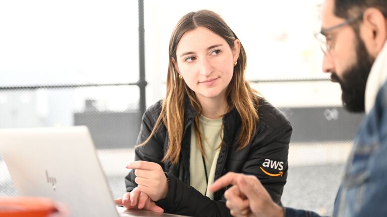 AWS employees meeting and reviewing a laptop device on a desk.