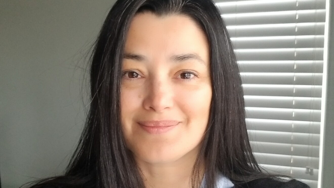 A woman smiles softly for a selfie in her home.