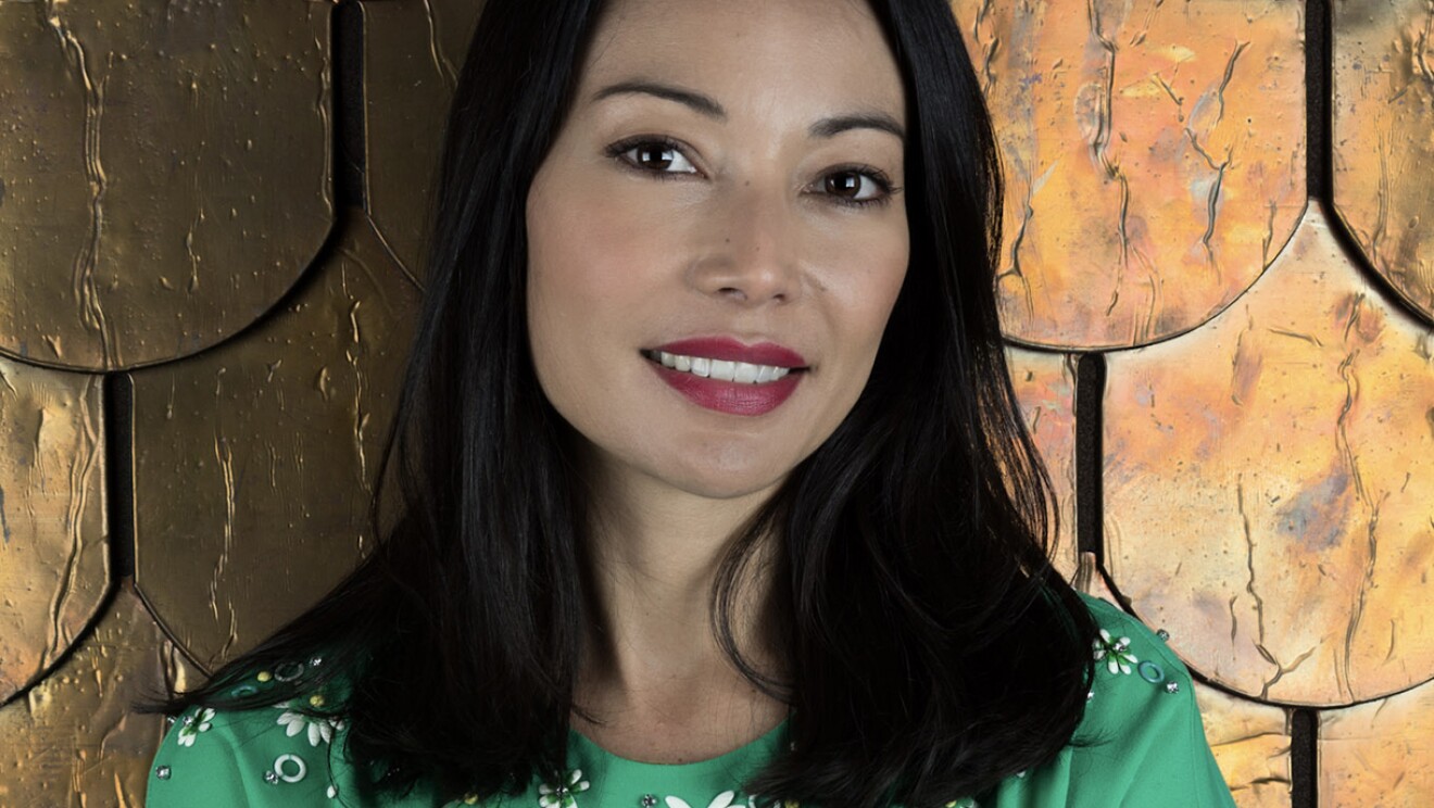 A woman smiles at the camera, her arms crossed in front of her.