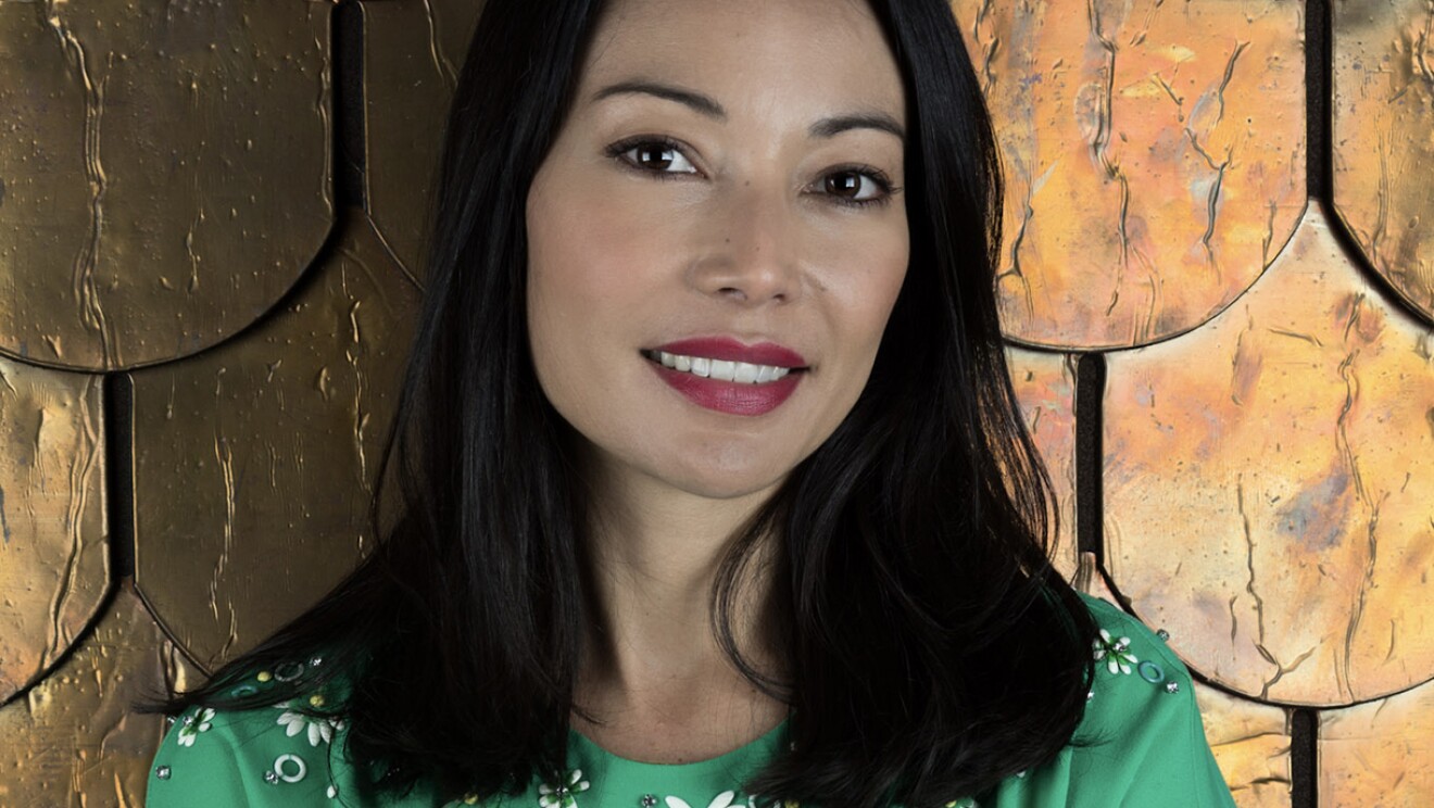 A woman smiles at the camera, her arms crossed in front of her. 