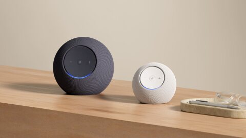 Echo Dot Max and Echo Studio on a wooden table next to a tray holding glasses