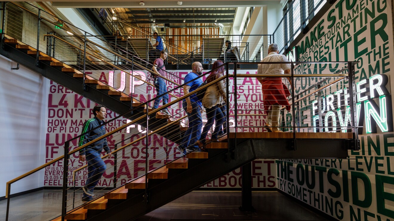 亚马逊员工爬上一组楼梯,上面装饰着鼓舞人心的标语,比如“尝试新事物”。