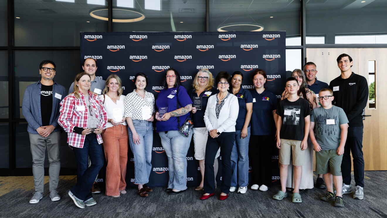 Group photo of diverse individuals in front of Amazon logo backdrop