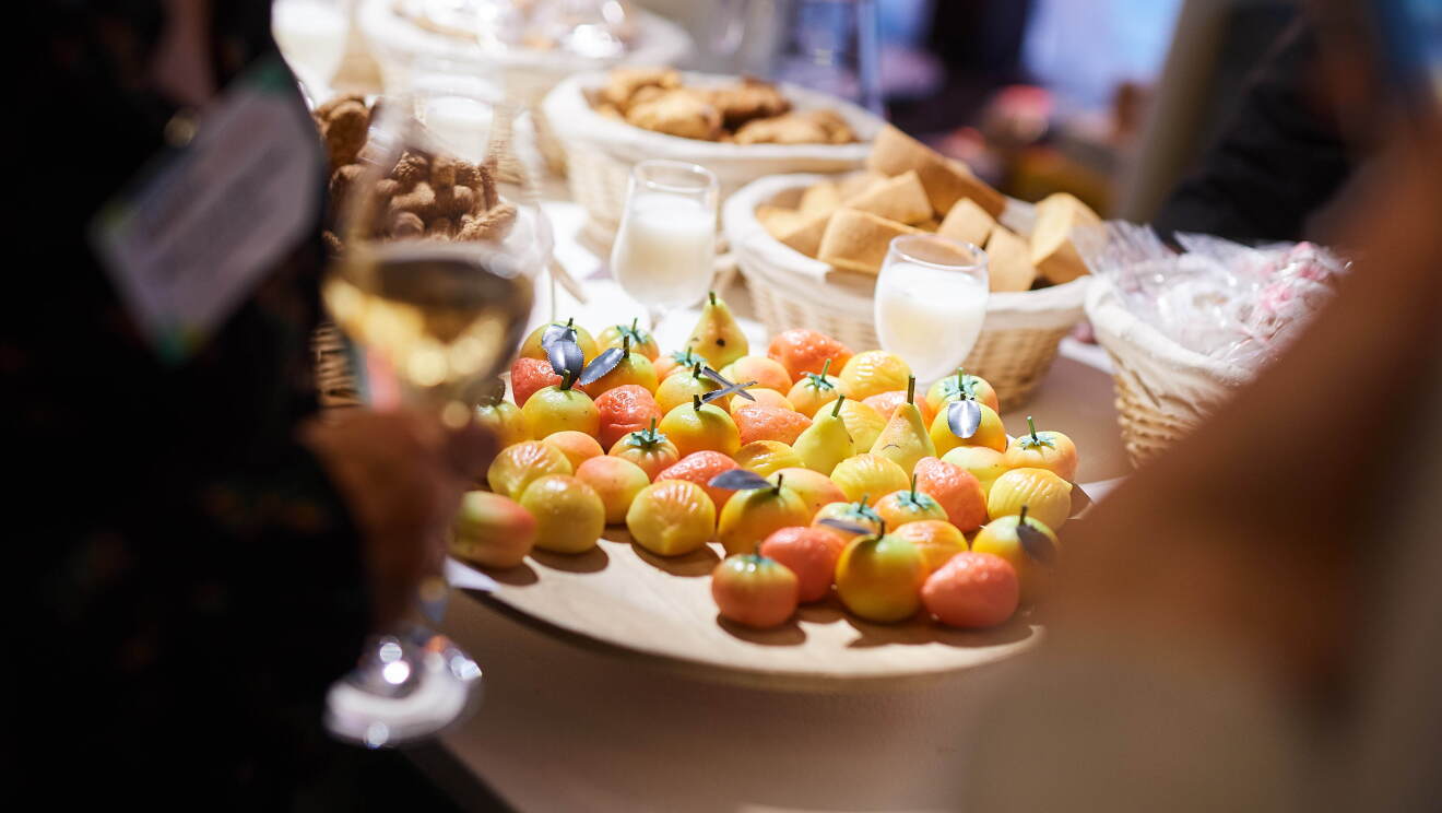 Rarezze, a Sicilian company offering a range of artisanal delicacies at Amazon Academy Brussels marketplace exhibition. This image focuses on almond pastries in the shape of yellow mini apples and oranges. 