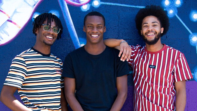 三位AfroPick创始人并肩站在艺术品前。