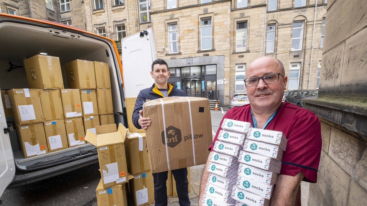 An image of the trtl team donating boxes of their products to key workers. They are holding stacks of boxes which they are unloading from a van.