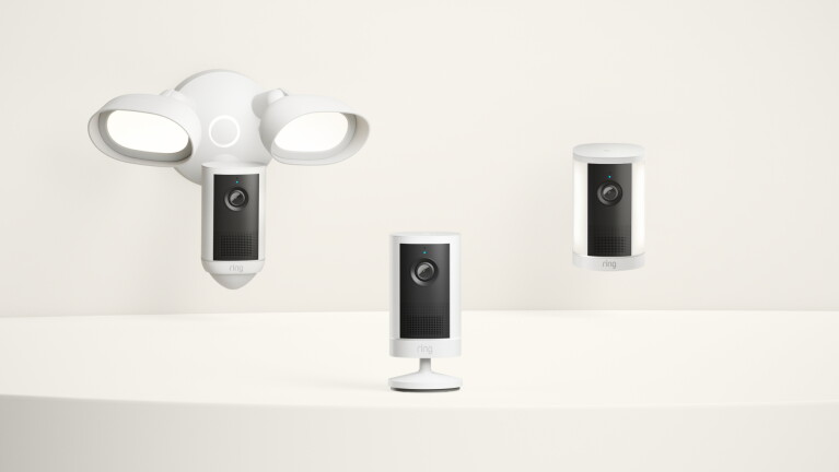 Three Ring security cameras in a lineup: floodlight cam, stick-up cam with mount, and stick-up cam on a flat surface