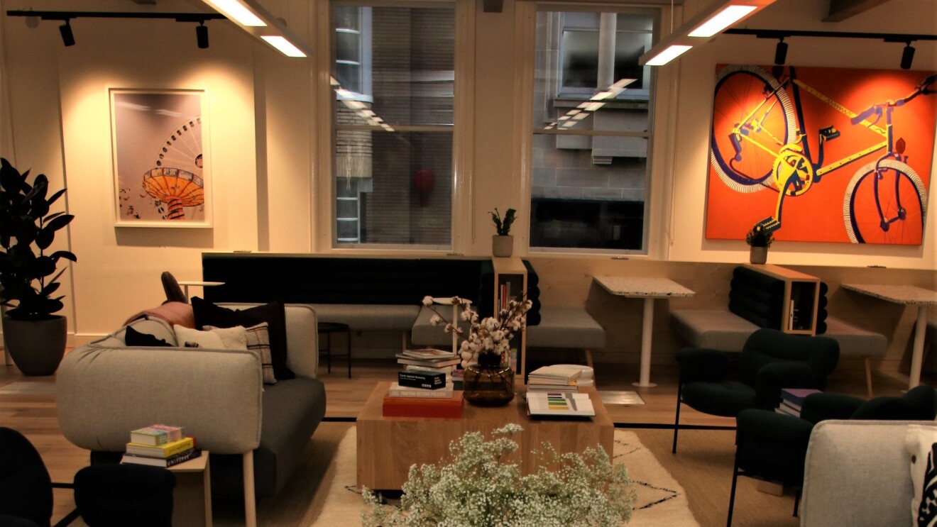 A photo of a social area in the Amazon Manchester offices. You can see a desk covered in books and sofas.