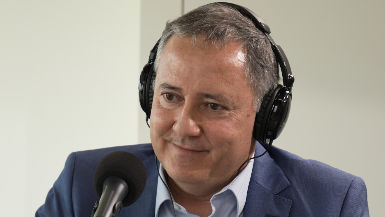 José Antonio Bretones, director de Crecimiento Internacional de la Empresa y Estrategias de Comercialización del ICEX (Instituto Español de Comercio Exterior), sentado en una mesa delante de un micrófono y con unos auriculares puestos y una sonrisa. Con una traje azul y una camisa azul muy clarito. Tiene el pelo corto y muy blanco. 