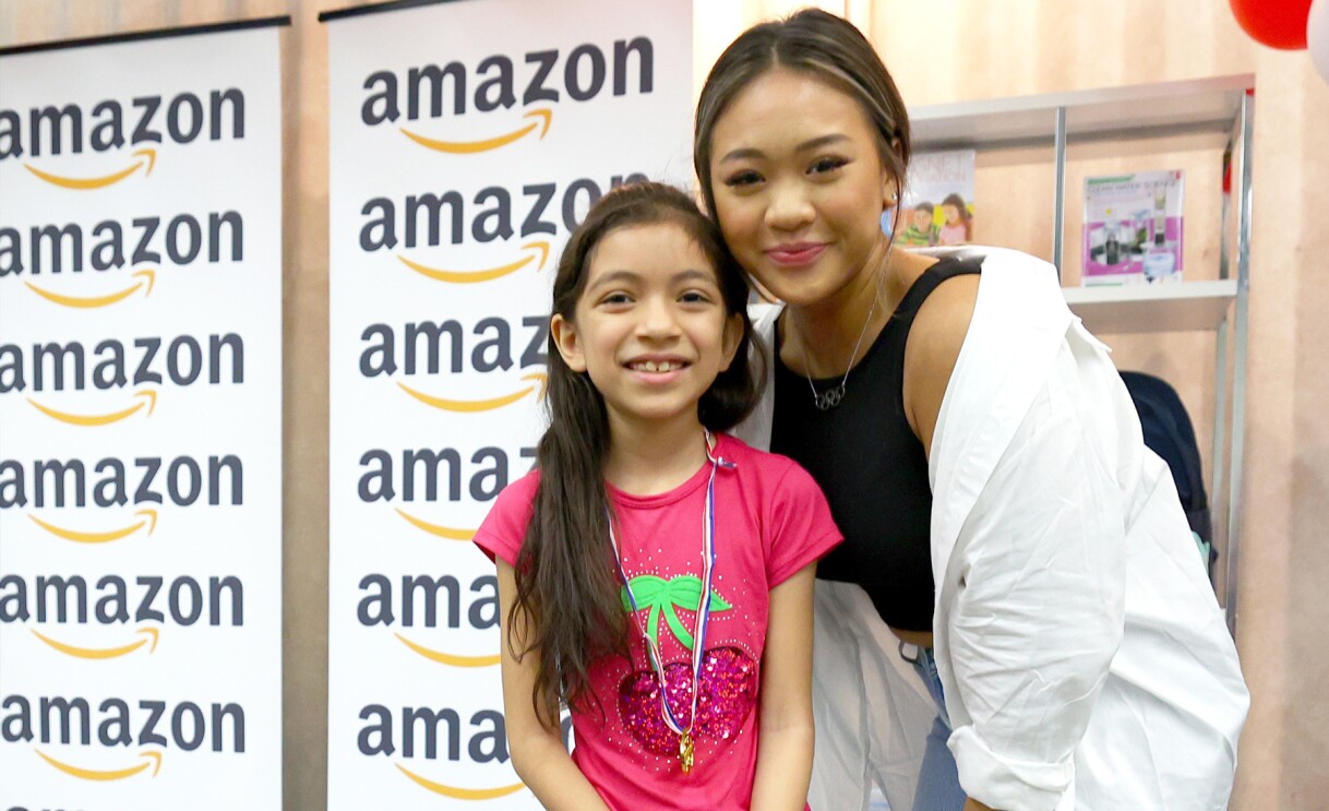 Suni Lee poses with students at an elementary school.