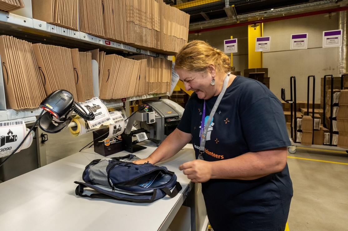 Logistik Mitarbeiterin packt einen Schulrucksack