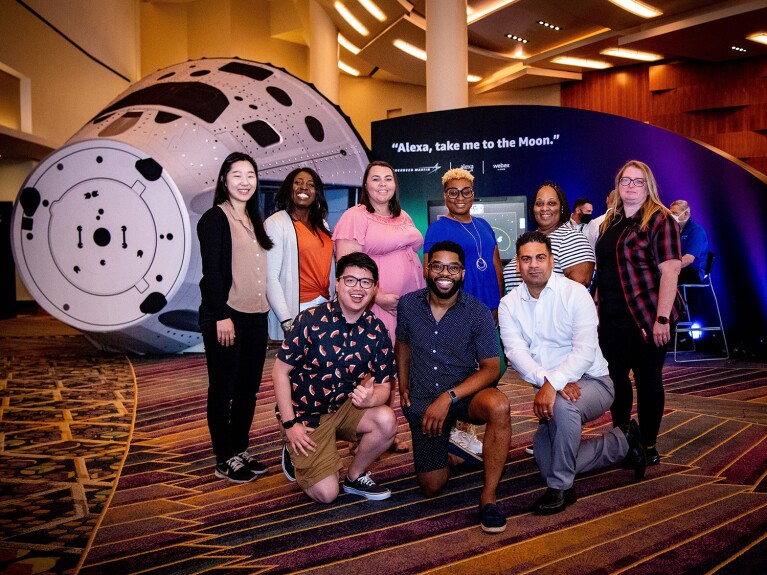 An image of eight Amazon Future Engineer Teacher of the Year award winners smiling for a photo in front of the mock space shuttle at re:MARS 2022 in Las Vegas.