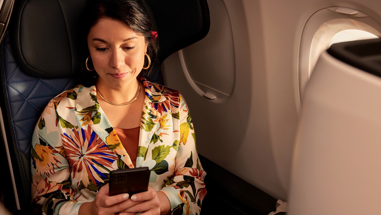 A photo of a passenger seated on an airplane, using their mobile device.