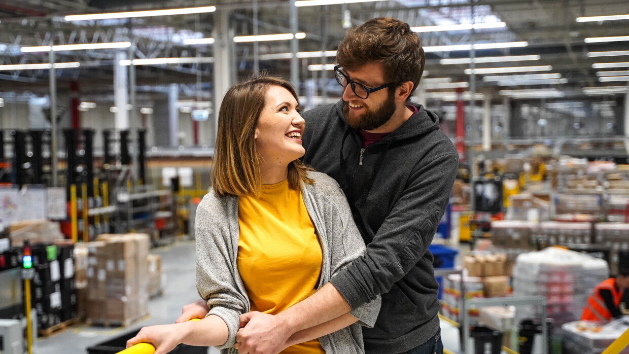 Dwóch pracowników Amazon, centrum logistyki w tle