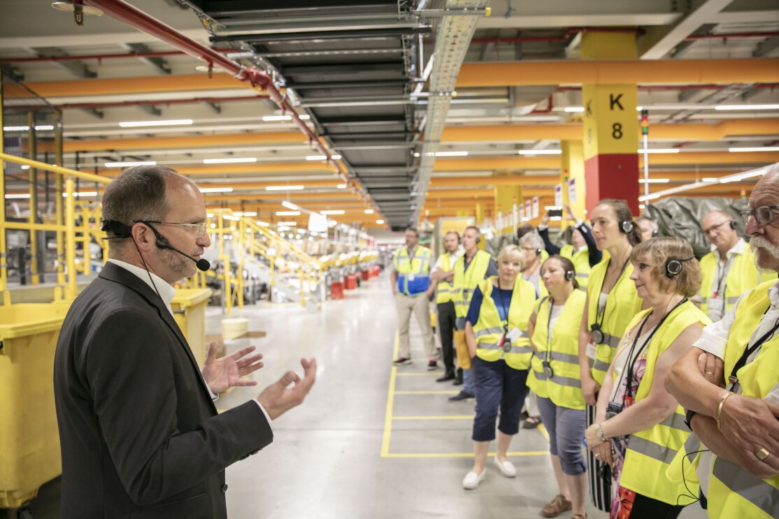 Ein Herr im grauen Anzug steht vor einer Gruppe von Besuchern in gelben Sicherheitswesten.