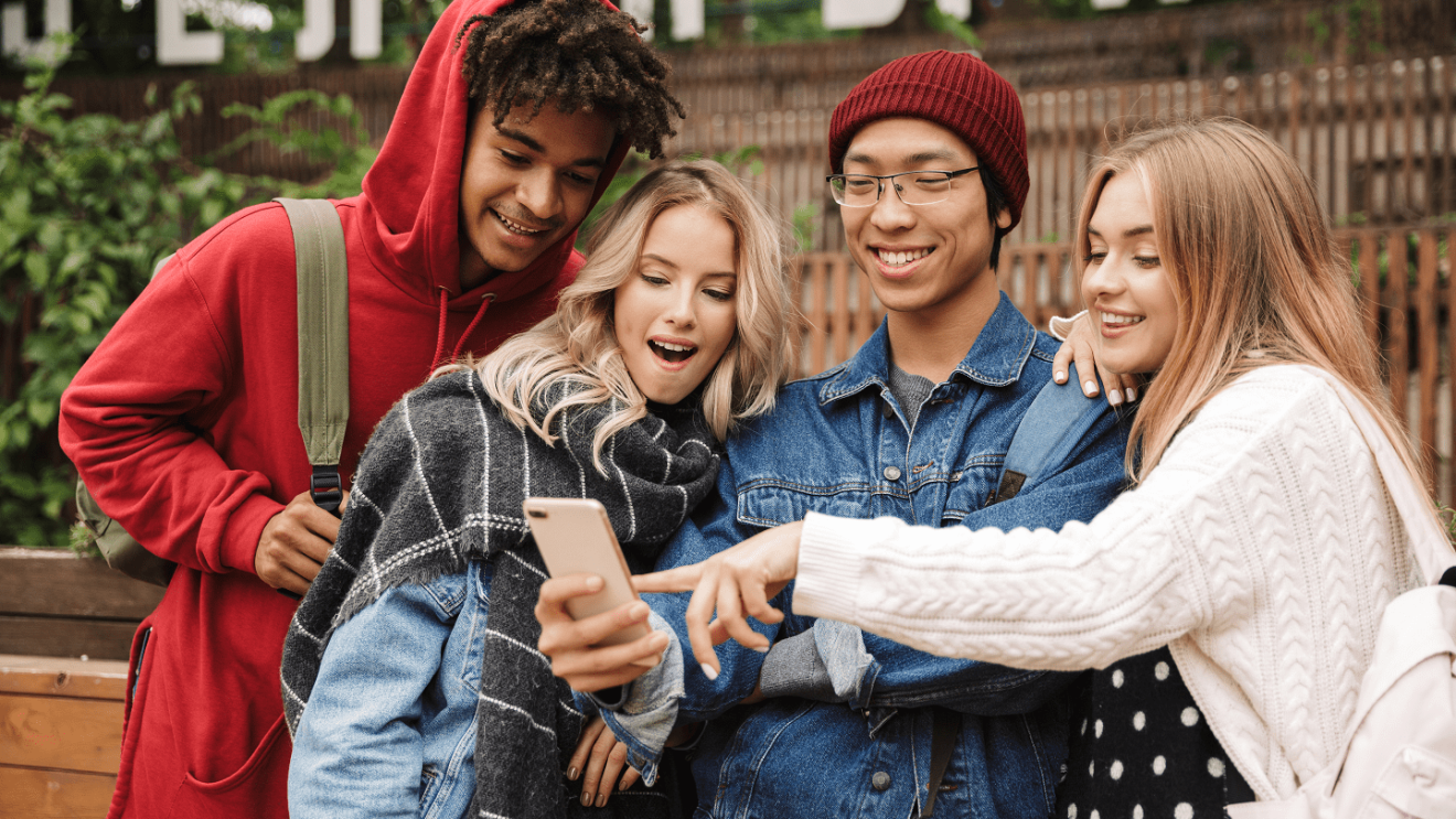 四个青少年聚在一起,兴奋地看着其中一个青少年的手机。