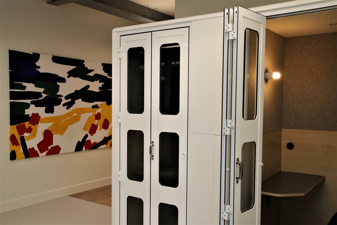 A futuristic privacy pod in Amazon's Manchester office, contrasting with colorful wall art behind it