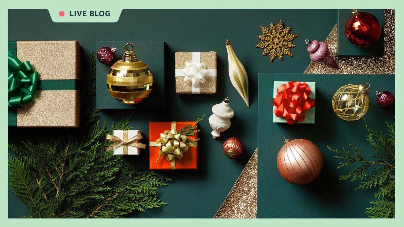 An image of various items against a hunter green background. The items include wrapped gifts in glittery gold paper with green and white bows and ribbons, tree ornaments of various shapes and sizes, and evergreen tree branches. There is a light green border around the whole image and a tag at the top that reads "LIVE BLOG" with a red dot next to it.