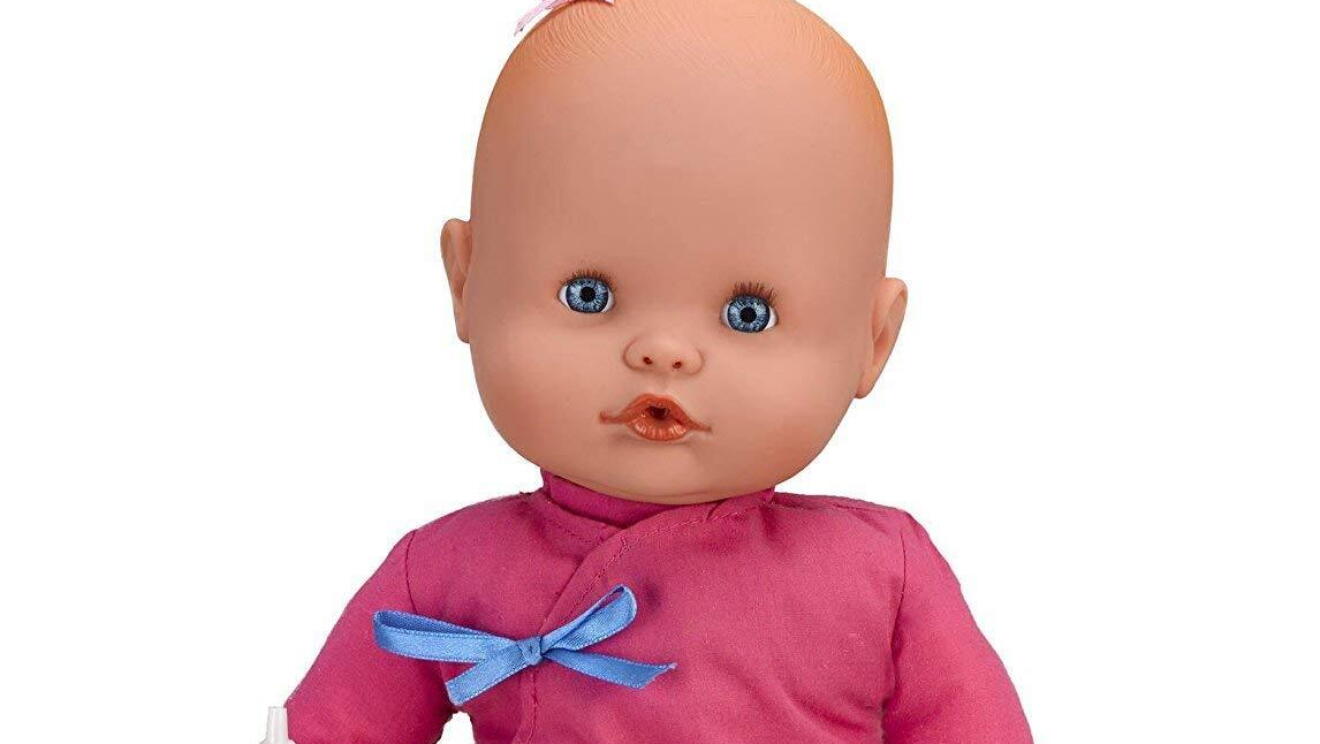 Muñeca rosa con un biberón en la mano derecha.