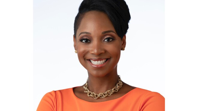 一个女人对着镜头微笑,她双手交叉在她的面前。