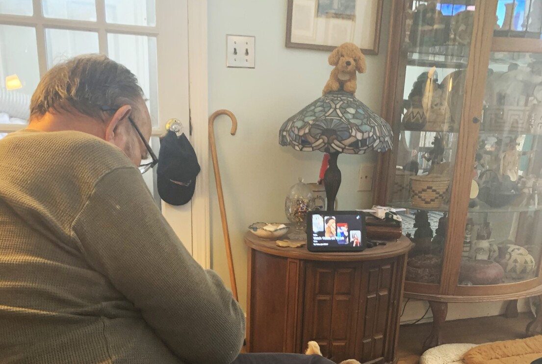 An image of a man sitting on his couch looking at his Echo Show device in the background.