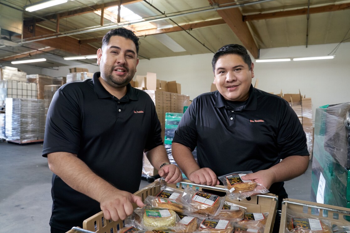 Anthony and Ronald stand by pallets of their packaged tortillas.