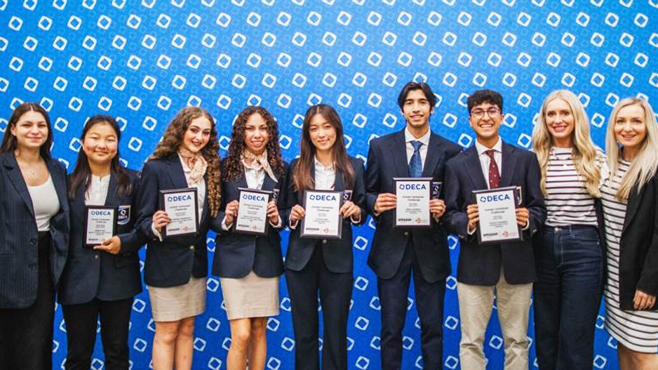  DECA event winners hold up a plaque while standing next to one another smiling. 
