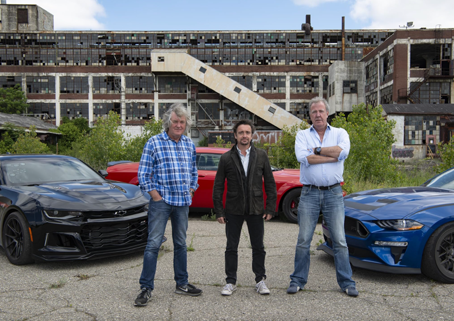 Three men (James May, Richard Hammond and Jeremy Clarkson) stand next to three cars