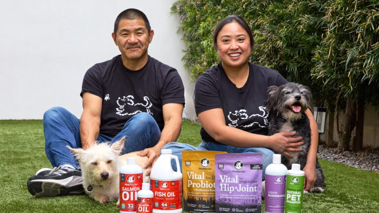 Two entrepreneurs sitting outdoors with dogs and their product line of pet health supplements