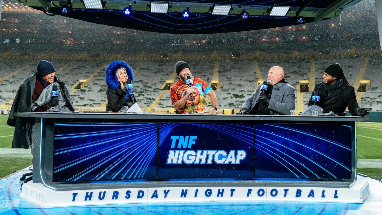 An image of the hosts of TNF Nightcap on set with the stadium behind them.