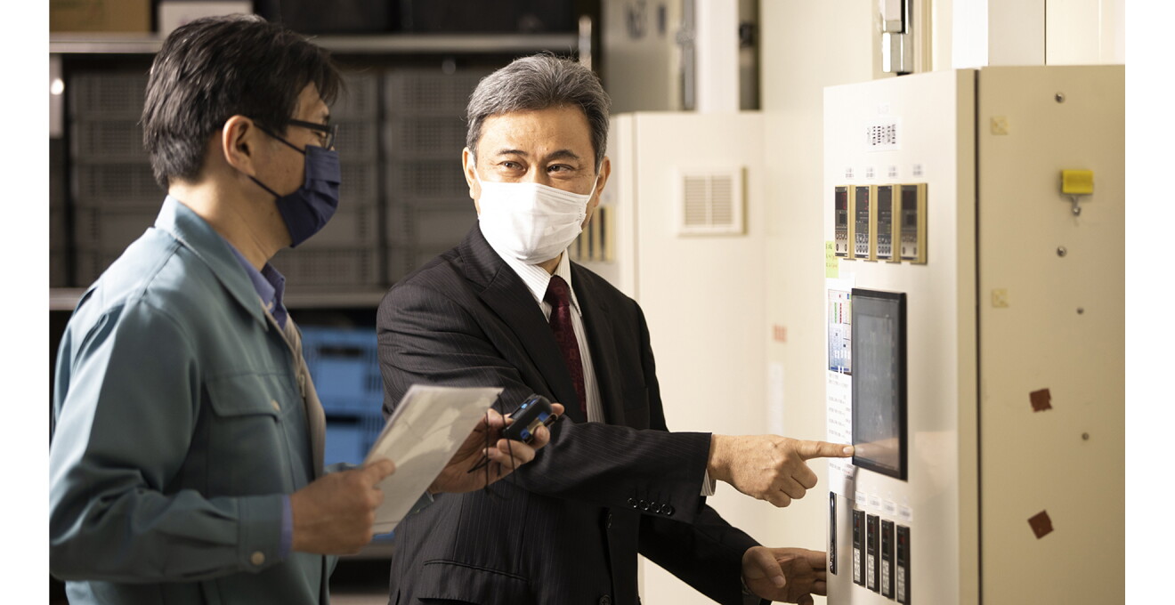 鳴瀨さんと米塚さんが設備の前で話している写真