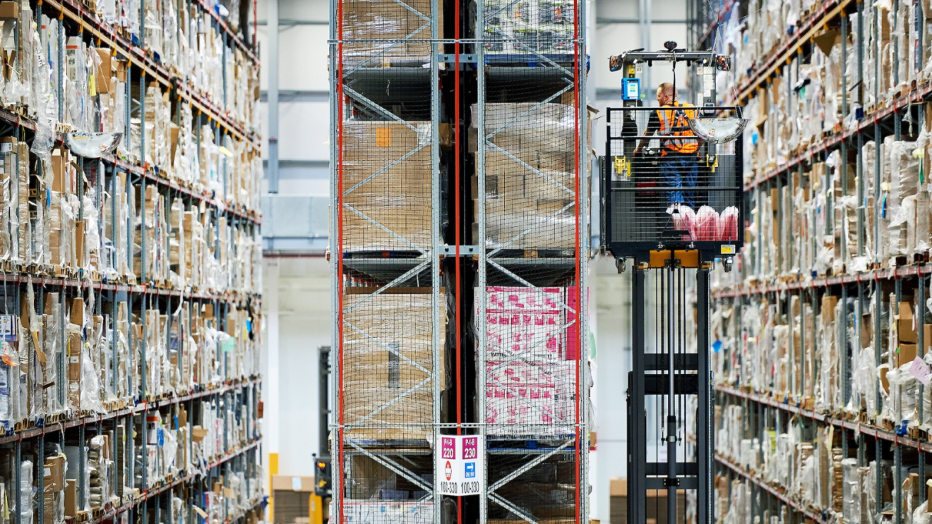 Massive shelves in Amazon fulfilment centre with man on lift retrieving items