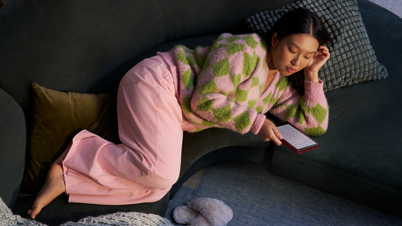 Une femme allongée lisant un Kindle Colorsoft sur un canapé